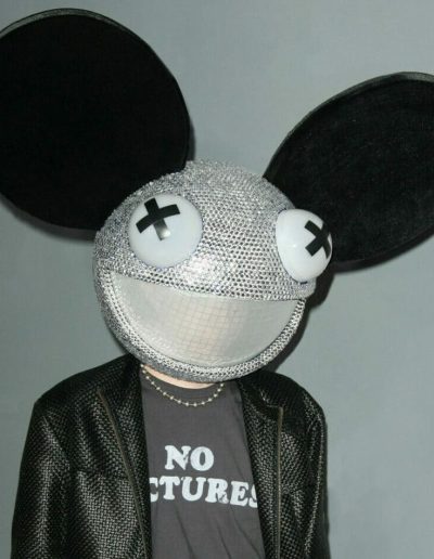 deadmau5 wearing a giant mouse head costume and a shirt that reads NO PICTURES.