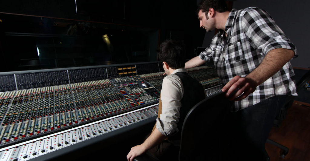Music Producers working on sounboard mixing a track to illustrate Mastering the Art of Mixing: Techniques and Tools for Audio Engineers in Los Angeles.